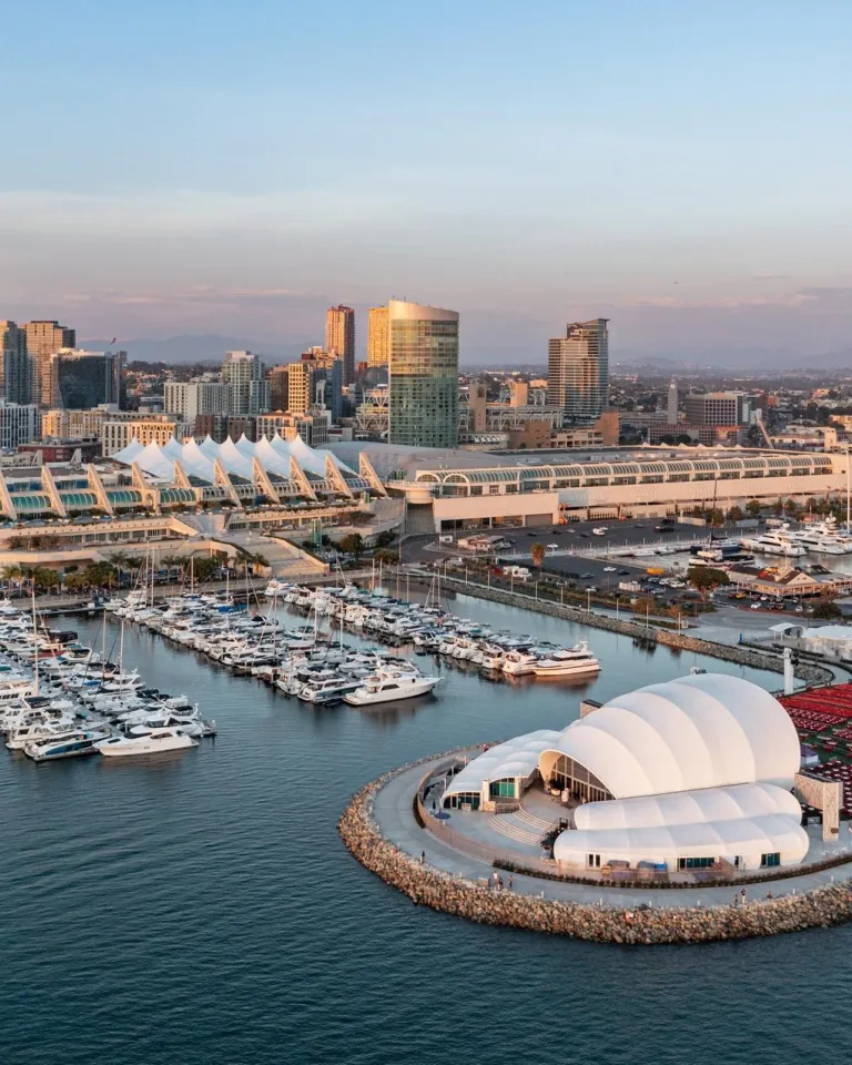 Aerial of San Diego Convention Center with the bay and Ray Shell at Jacobs Park in the foreground and downtown San Diego and blue skies in the background