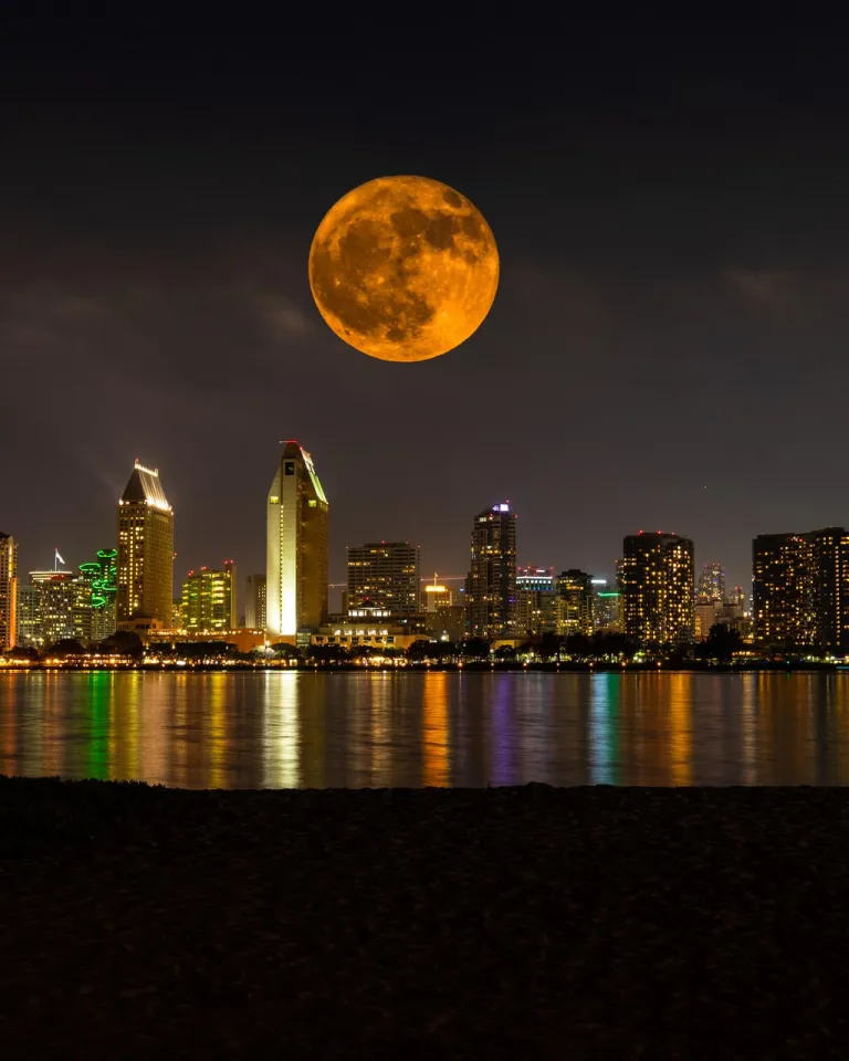 Full moon above San Diego skyline on a dark night