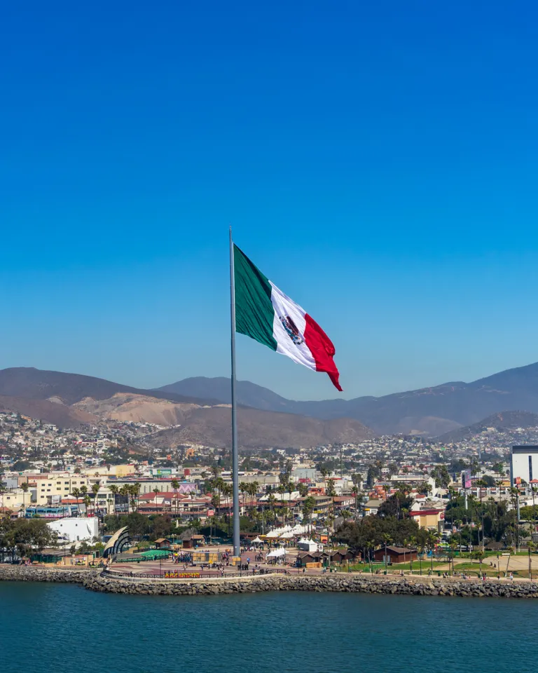 Port of Ensenada with a large flag of Mexico towing over the waterfront promenade