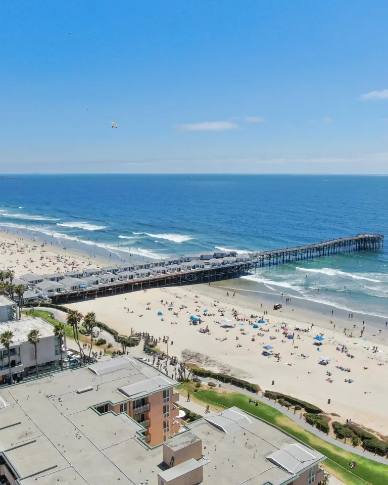 Aerial view of Crystal Pier in Pacific Beach, San Diego, showing the sandy beach, ocean waves, and the pier extending into the Pacific.