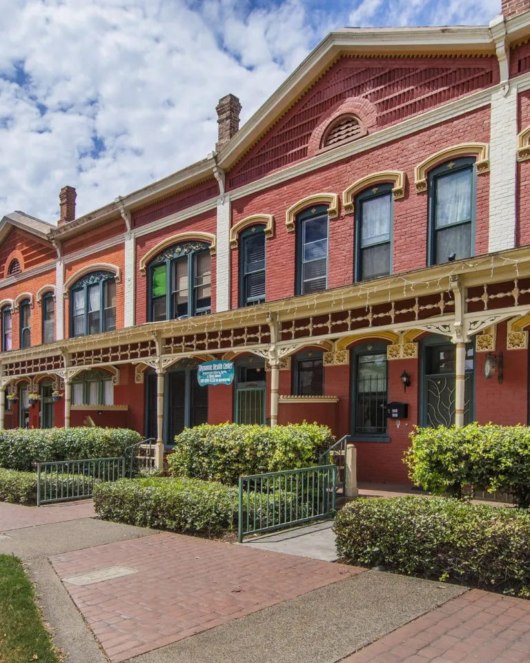 A view of the Kimball Block in National City near San Diego, showing a red brick exterior and multiple planters.