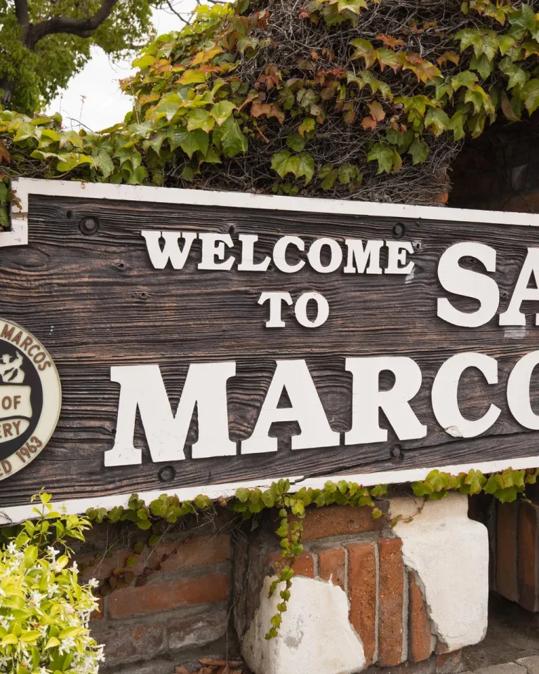 A sign reading "Welcome to San Marcos" is depicted in the San Marcos neighborhood of San Diego County.