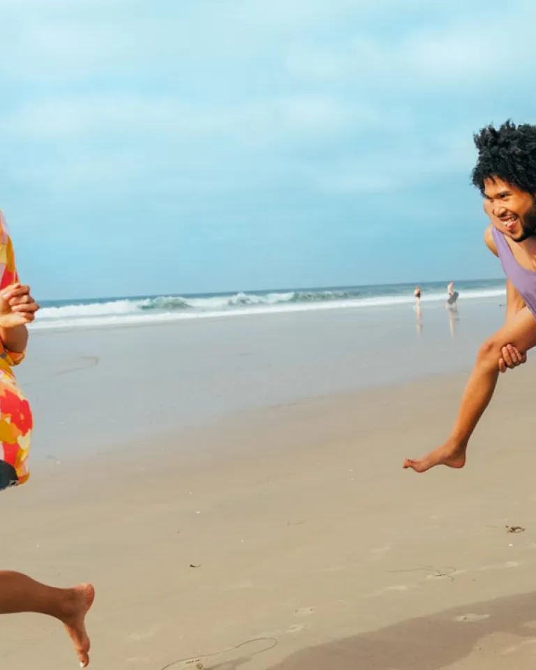 Kid gets piggy back ride from father while running on San Diego beach after mother