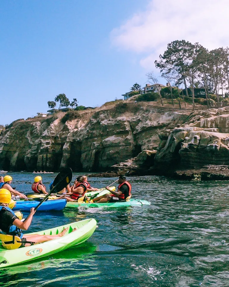 People on the ocean kayaking through La Jolla's sea caves in San Diego, CA