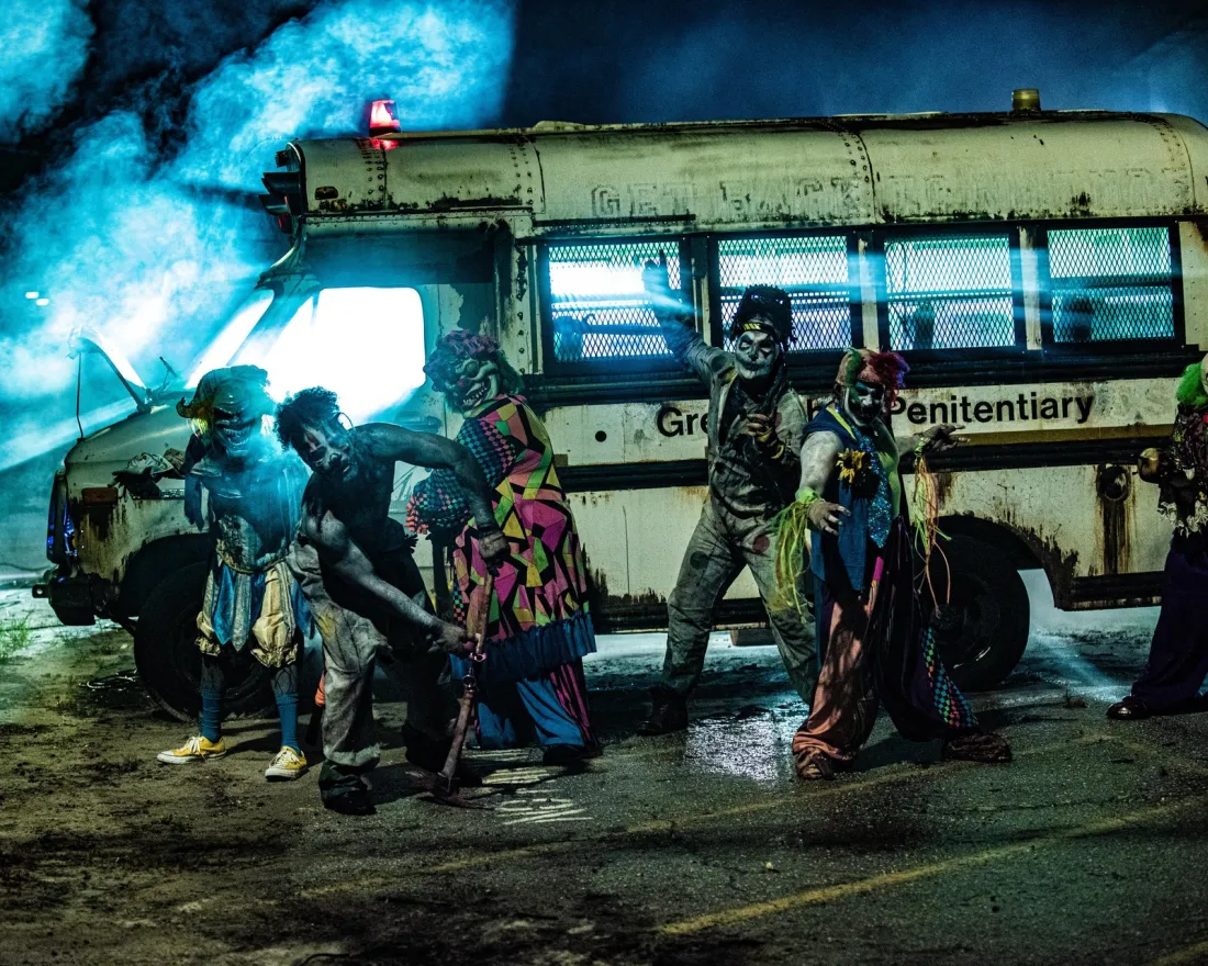 a group of people dresses as zombies and monsters in front of a haunted school bus in San Diego.