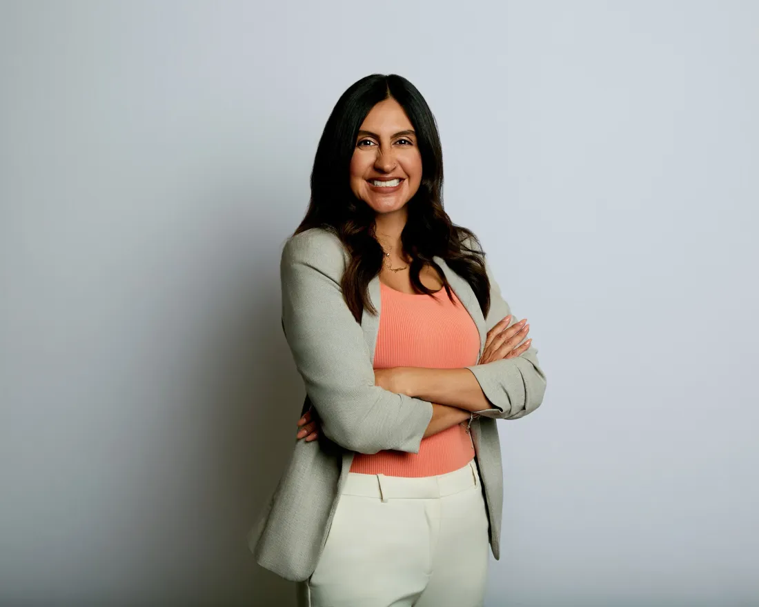 woman standing with arms folded and smiling for photo
