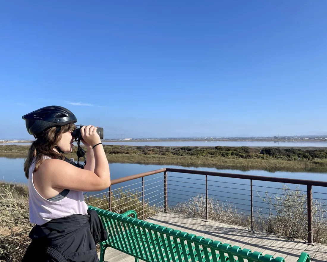 Woman with binoculars exploring a wetlands area in San Diego