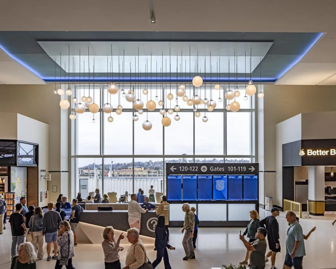 Travelers waiting at Terminal 1 San Diego Airport with art overhead