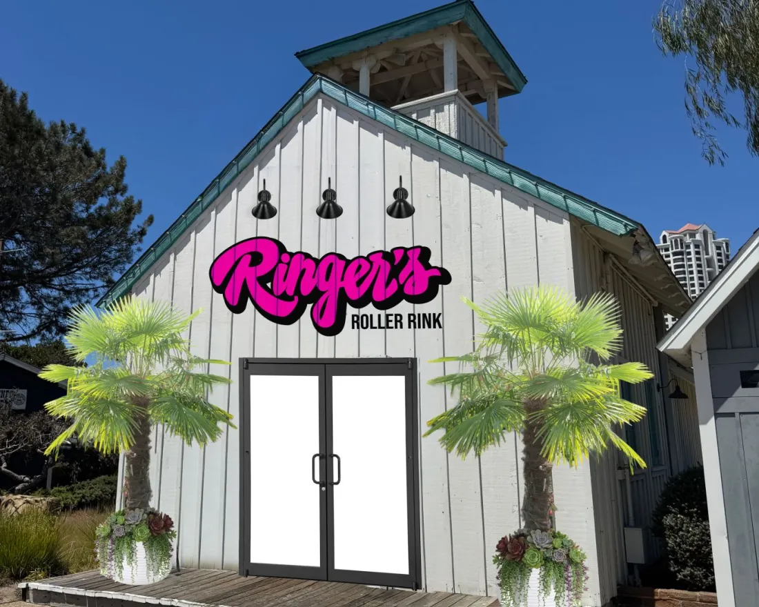 Exterior of Ringer’s Seaport roller rink at Seaport Village in San Diego, featuring a white barn‑style building with the Ringer’s Roller Rink sign, palm trees in planters, and a clear blue sky.