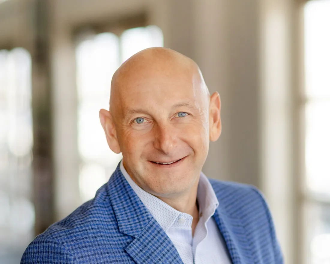 Daniel Kuperschmid in a blue blazer stands in a bright indoor setting, slightly smiling.