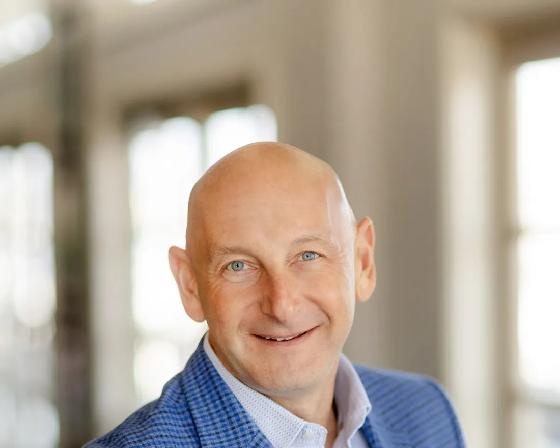 Daniel Kuperschmid in a blue blazer stands in a bright indoor setting, slightly smiling.
