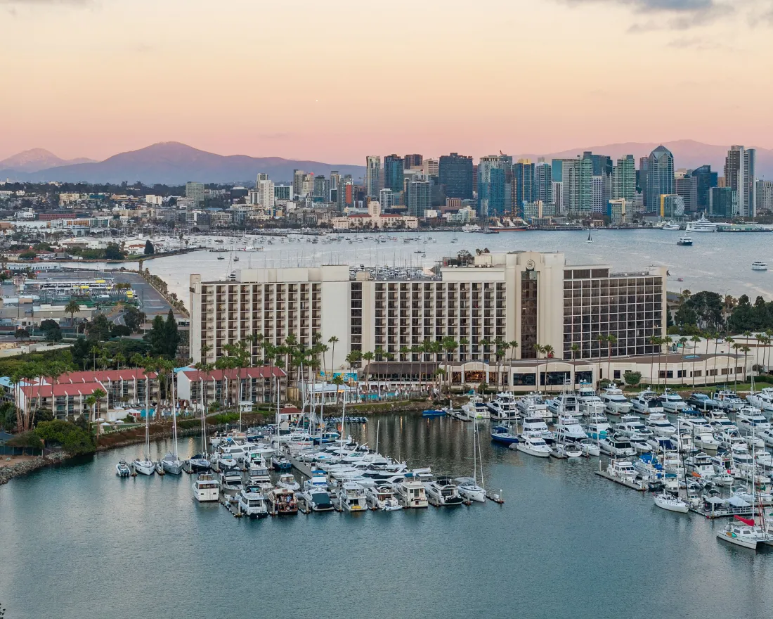 Sheraton San Diego Resort - View of a marina with yachts, a hotel, and a city skyline at sunset.