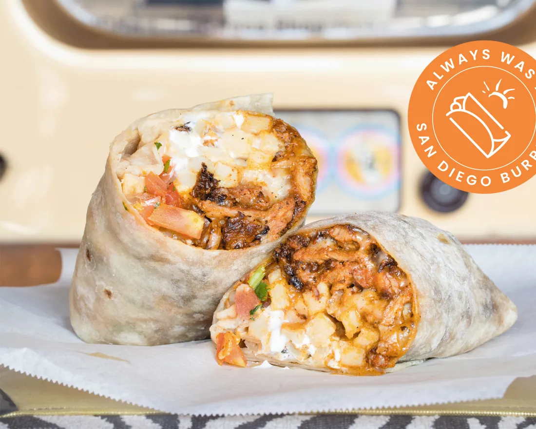 Close-up of two burritos filled with rice, beans, and toppings, against a soft background.