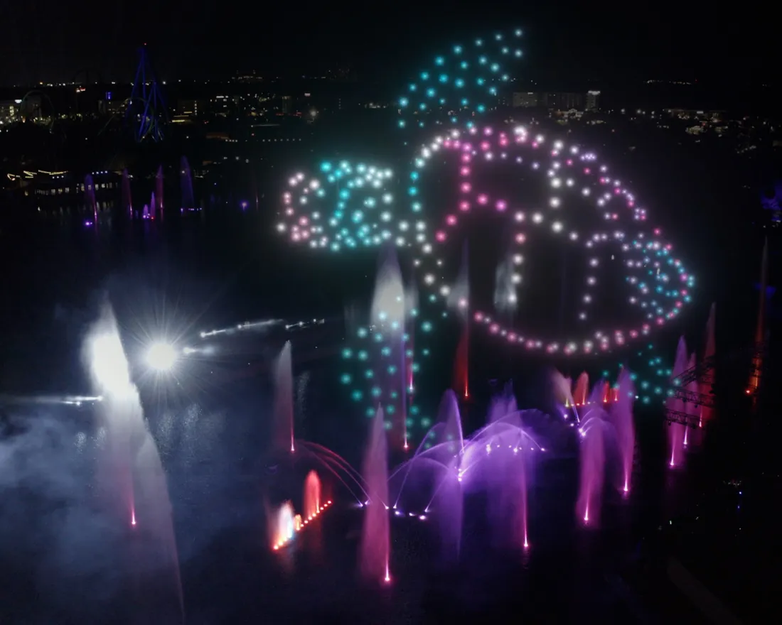 A turtle illuminated by colorful lights amid a nighttime water fountain display form the new summer drone show at SeaWorld San Diego, Ocean of Dreams.