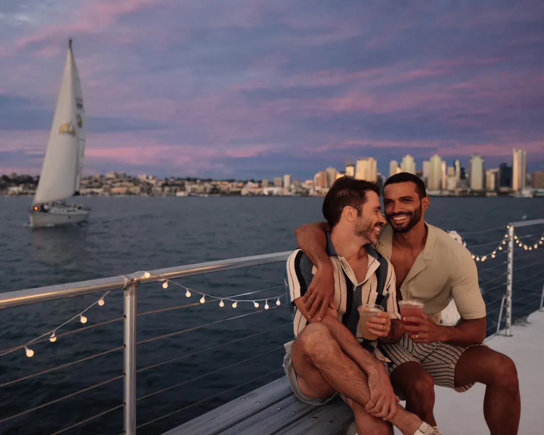 Two men sitting on a Triton yacht in San Diego, enjoying each other's company against a sunset backdrop.