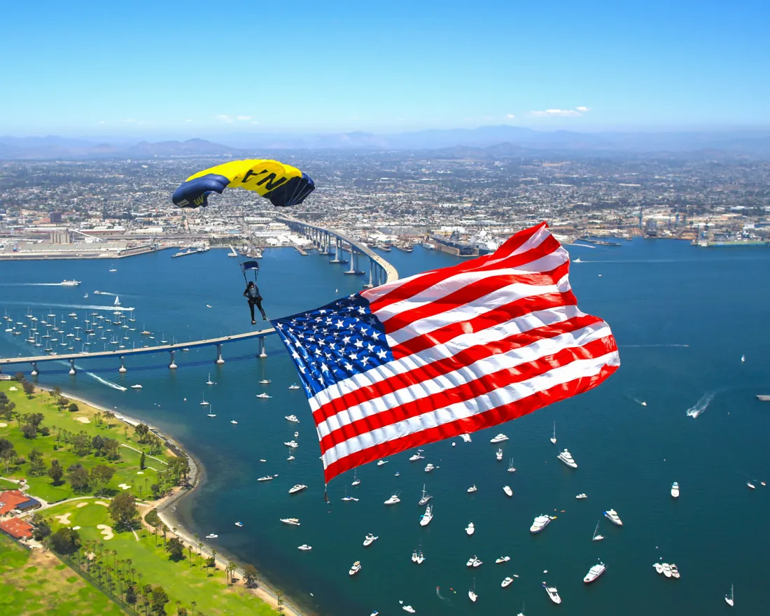 Skydiver descending with a large American flag over San Diego