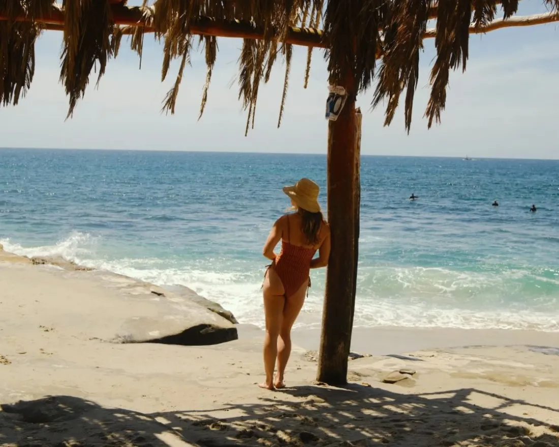 A woman leaning against a pole of the windansea shack in La Jolla San Diego