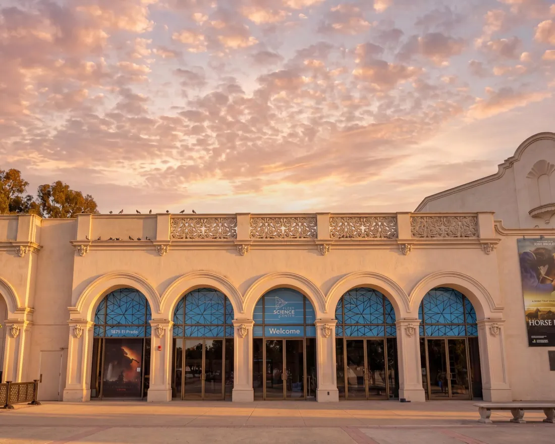 Historic Fleet Science Center with arched windows under a colorful sunset sky in Balboa Park.