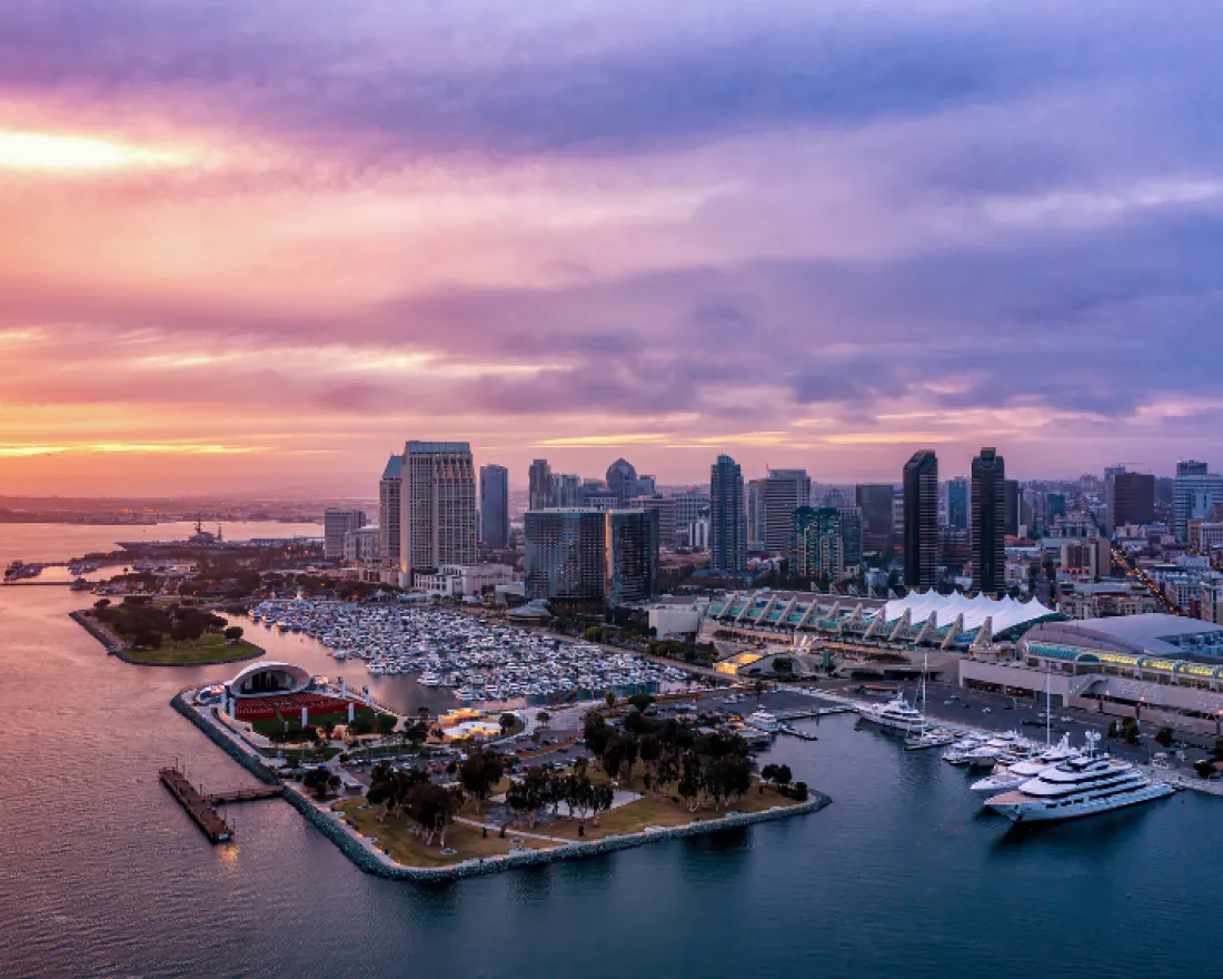 Sunset view over San Diego skyline with boats docked along a waterfront.