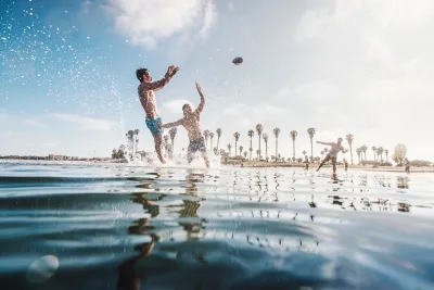 3 people playing football in the water at Mission Bay in San Diego