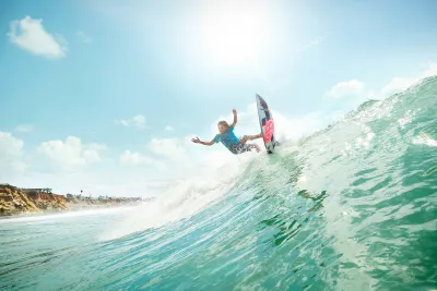 Young man catching an epic wave on a surfboard with a smile graphic in San Diego