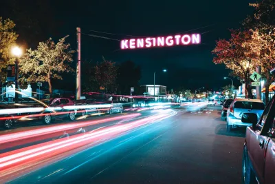 Kensington Neighborhood sign over a nighttime time-lapse of car lights streaks.