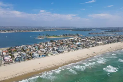 Aerial of Mission Beach boardwalk and waterfront houses and vacation rentals with Mission Bay in the background