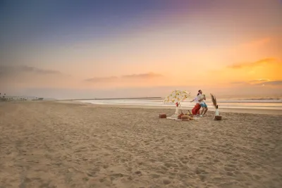A couple dancing with each other on the beach at sunset next to a fire pit in San Diego