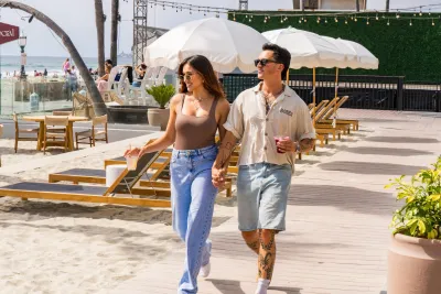 A couple strolls along a wooden walkway through FIT Social under sunny skies in the Pacific Beach community of San Diego.