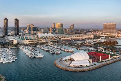 Aerial of San Diego Convention Center with the bay and Ray Shell at Jacobs Park in the foreground and downtown San Diego and blue skies in the background