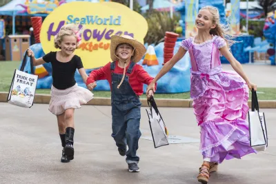 Three kids walking down the street at SeaWorld San Diego in costumes during Spooktacular