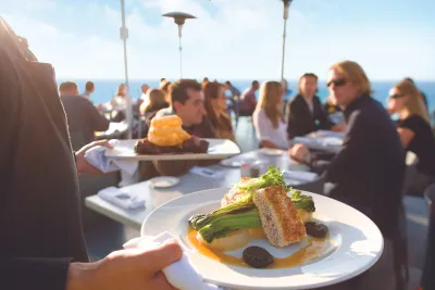 Server bring dinner plates to diners at George's at the Cove in San Diego's La Jolla