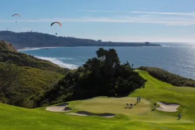 Golfers at Torrey Pines Golf Course overlooking the ocean with paragliders