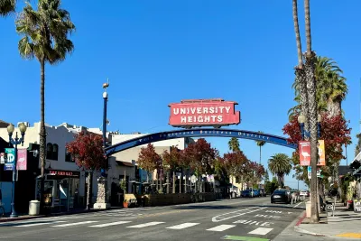 Neighborhood sign of University Heights of a red trolley overarching the main street of the neighbodhood