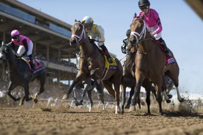 Three horses racing on the race track at Del Mar Thoroughbred Club in San Diego