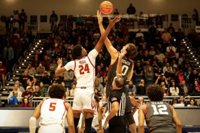 Two male college basketball players jumping up for a a jump ball at the start of a game at the Rady Children's Invitational in San Diego