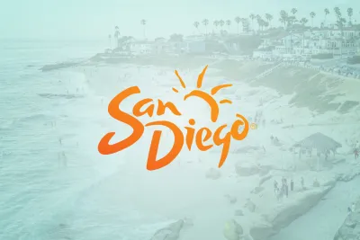 A beach scene with people walking and relaxing near the ocean, overlaid with the orange "San Diego" logo and a sun graphic.