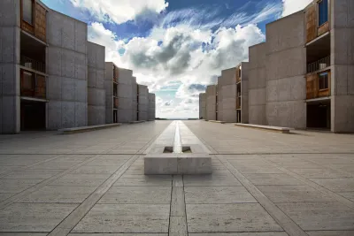 A view of the Salk Institute in the La Jolla neighborhood of San Diego, with symmetrical buildings on each side stretching to a view of the ocean on the horizon.