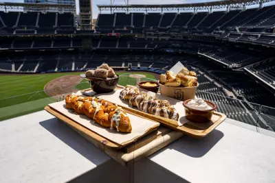 A plate of new Petco Park food offerings for 2026 is depicted against a backdrop of the San Diego ballpark.