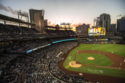 Petco Park stadium filled with Padres fans, overlooking the field at sunset with city skyline in background.