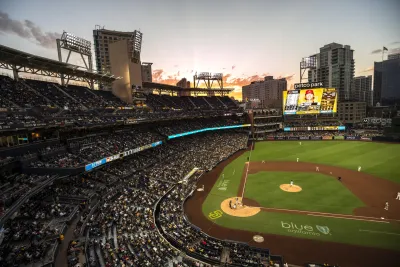 Petco Park stadium filled with Padres fans, overlooking the field at sunset with city skyline in background.
