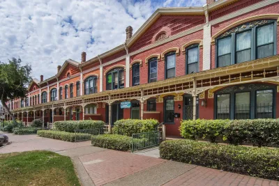 A view of the Kimball Block in National City near San Diego, showing a red brick exterior and multiple planters.