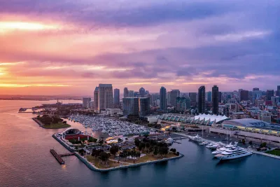 Aerial view of a vibrant San Diego skyline at sunset, reflecting colors on the water.