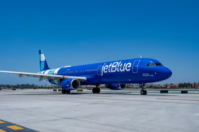 JetBlue airplane on runway under a clear blue sky.