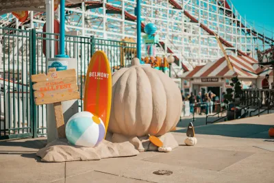 A large sand sculpture of a pumpkin with a beach ball and surfboards during the Beachside Fall Fest at Belmont Park in San Diego.