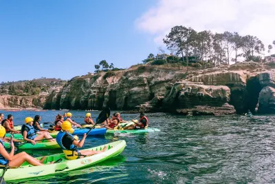 People on the ocean kayaking through La Jolla's sea caves in San Diego, CA