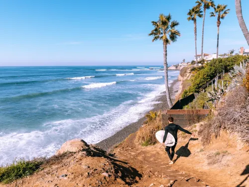 Surfer heading onto beach in Bird Rock in San Diego 