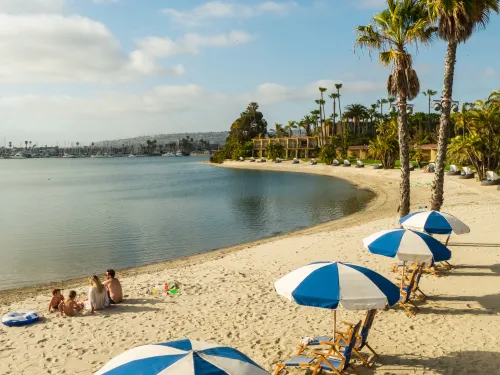 Family enjoying the sand Mission Bay with cabanas and the Bahia Resort behind them
