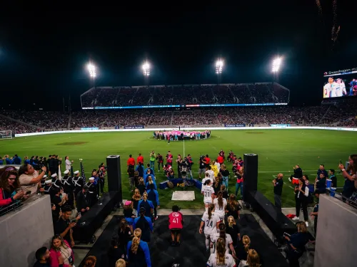 San Diego Wave FC walks onto snapdragon stadium field at night, with a crowd filling the stands under bright stadium lights.