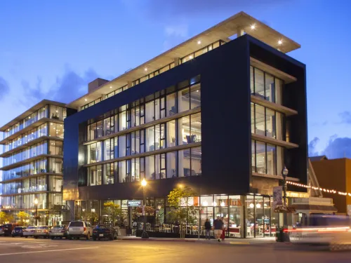 A building with a lot of windows on the corner of two streets at dusk in San Diego
